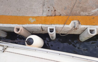 Fenders and dock bumpers suspended between a boat and dockside for protection. Maritime fenders.